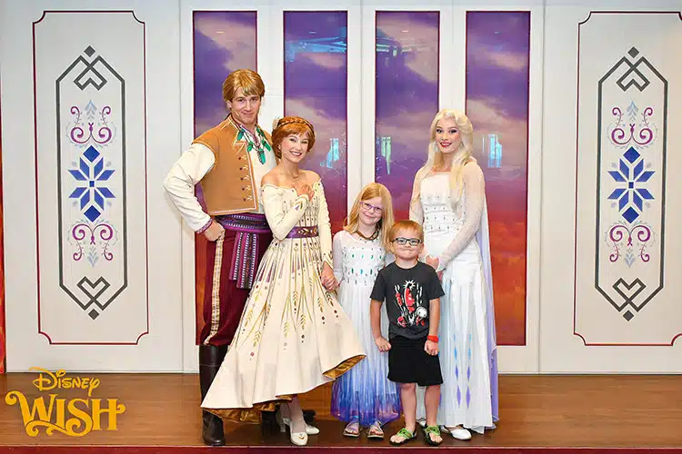 a boy and girl posing with Anna, Elsa, and Kristoff from Frozen after Olaf's Royal Picnic aboard the Disney Wish