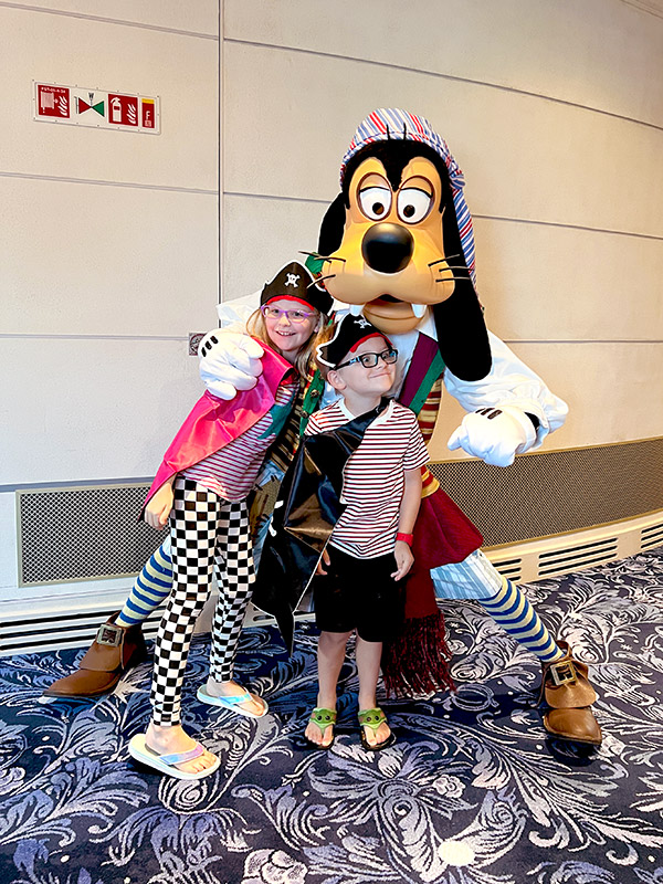 two children dressed as pirates posing with Pirate Goofy on the Disney Wish