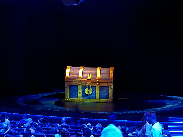 a giant treasure chest on the Walt Disney Theatre stage before a performance of The Little Mermaid on Disney Wish