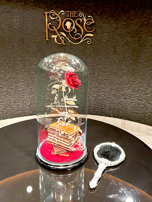 closeup of the enchanted rose under a cloche next to the magic mirror at the entrance of The Rose lounge on Disney Wish