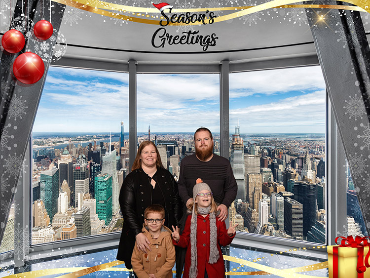 a family in a souvenir photo taken at the Empire State Building with "Season's Greetings" at the top