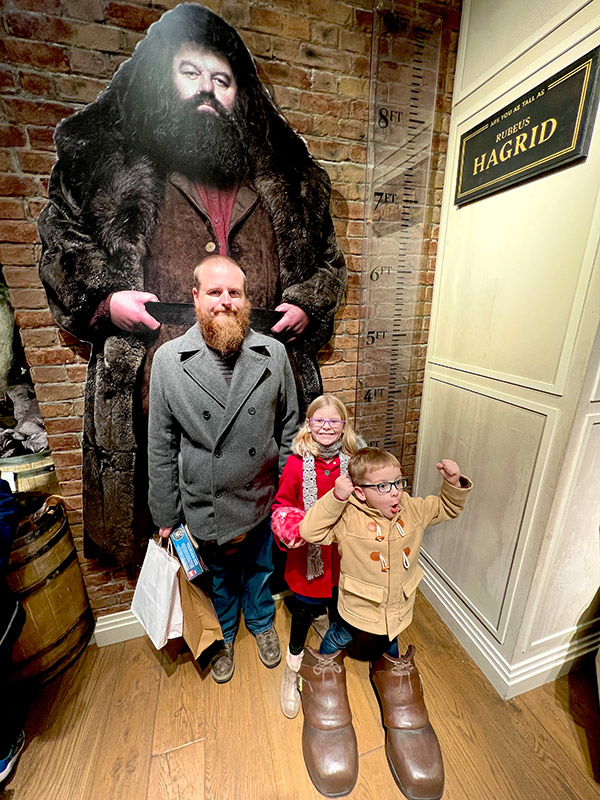 a father, daughter, and son posing in front of a large Hagrid wall print in Harry Potter New York