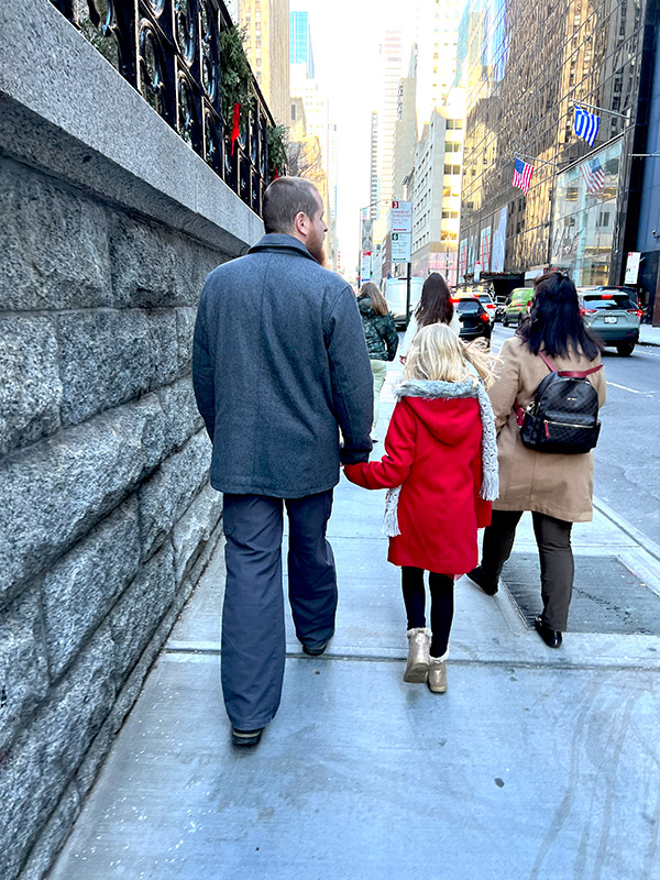 a father and daughter walking through the streets of Manhattan at Christmas time