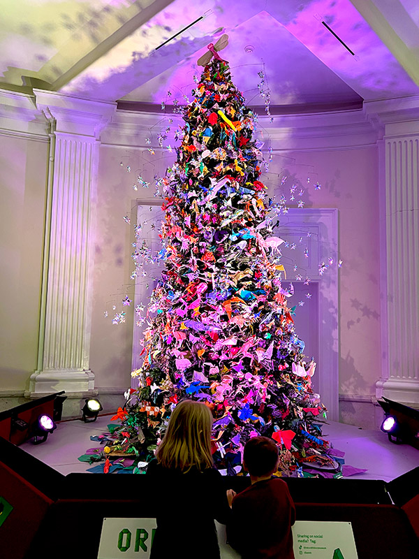 kids looking at the Christmas tree in the American Museum of Natural History decorated in origami ornaments