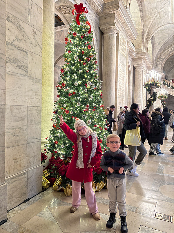 kids posing in front of a Christmas tree inside the Stephen A. Schwarzman branch of the New York Public Library