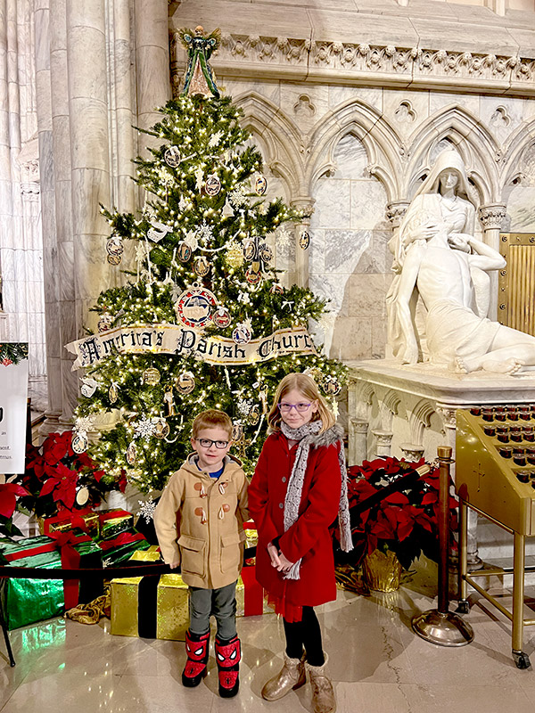 two kids posing in front of a Christmas tree inside St. Patrick's Cathedral in New York City