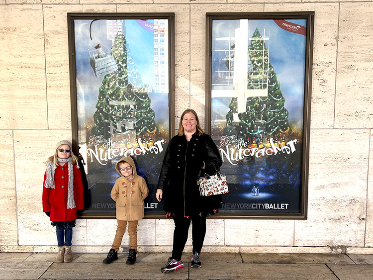 a mother, son, and daughter posing in front of The Nutcracker ballet posters outside the Lincoln Center