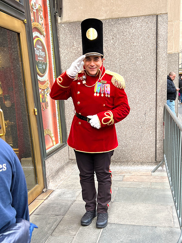 a man dressed as a toy soldier saluting guests outside the entrance of FAO Schwarz in New York City