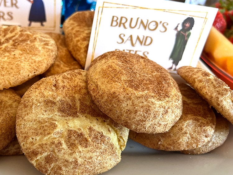 closeup on a platter of snickerdoodle cookies with a card featuring Bruno from Encanto and the text "Bruno's sand bites"