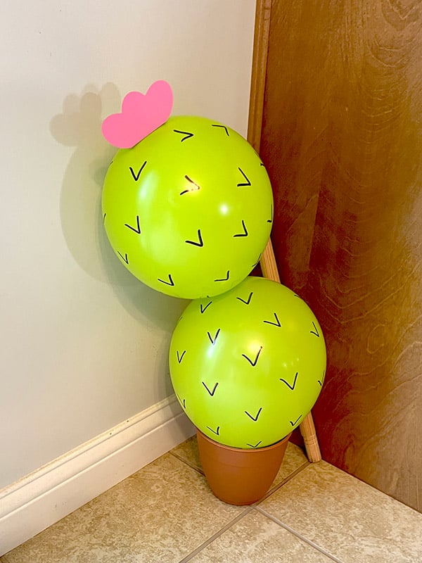 green balloons in a planter made to look like a cactus with sharpie spines drawn on
