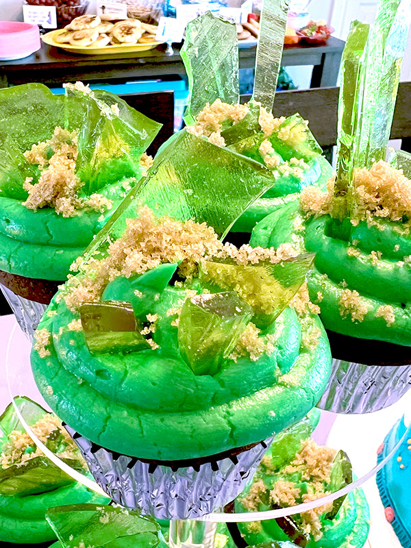 Bruno-inspired Encanto themed cupcakes with green frosting, brown sugar sand and green candy glass shards