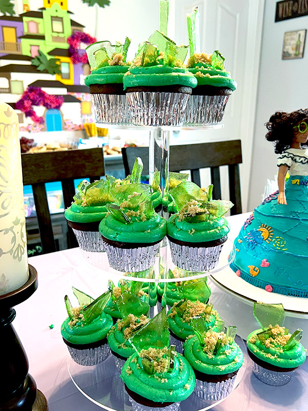 a three-tier cupcake stand full of Encanto themed cupcakes