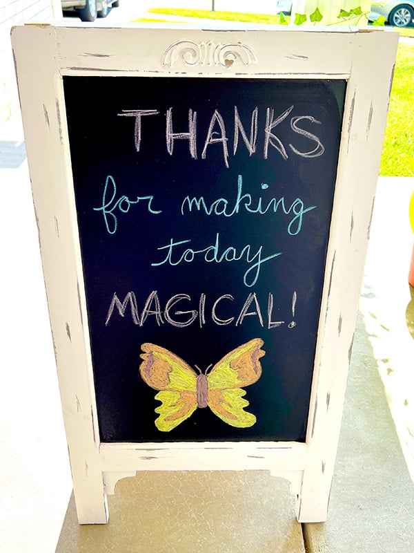 standing chalkboard sign that reads "Thanks for making today magical!" with an orange and yellow butterfly drawn in chalk