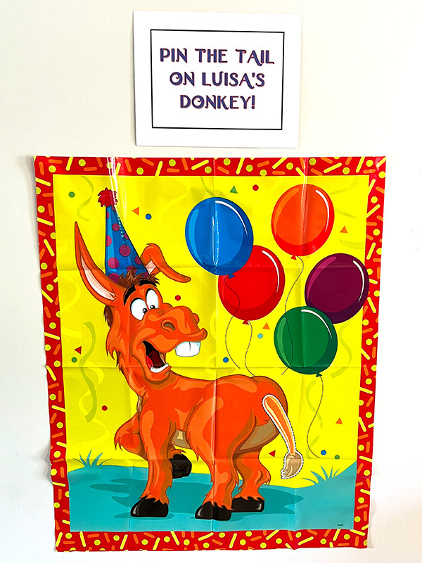 a pin the tail on the donkey game on the wall with a sign above reading "Pin the tail on Luisa's donkey!"