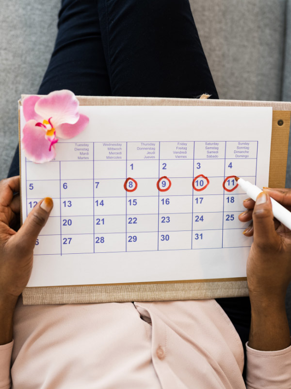 woman circling a fertility calendar in red to determine her ovulation period