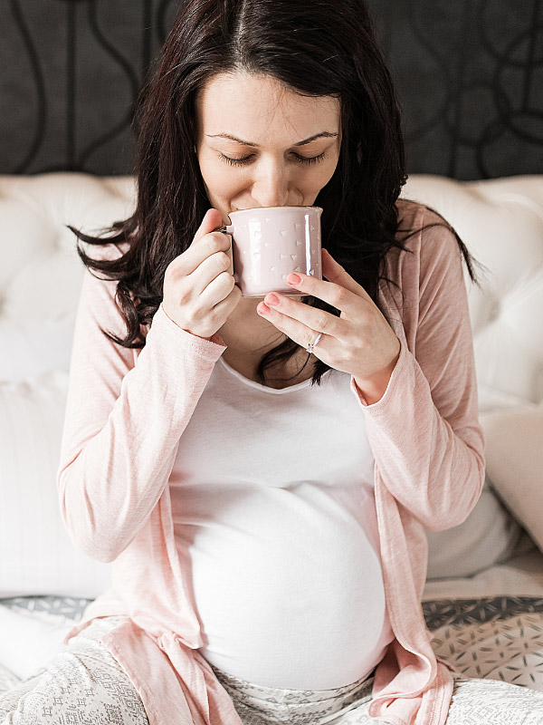 pregnant woman in the third trimester sipping a chai tea latte from a mug
