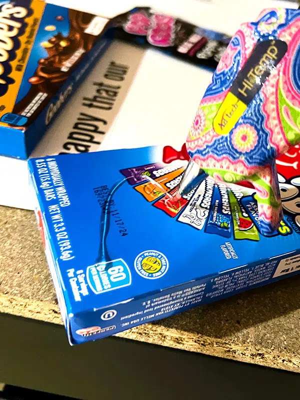 closeup up of applying hot glue to the back of an Airheads candy box