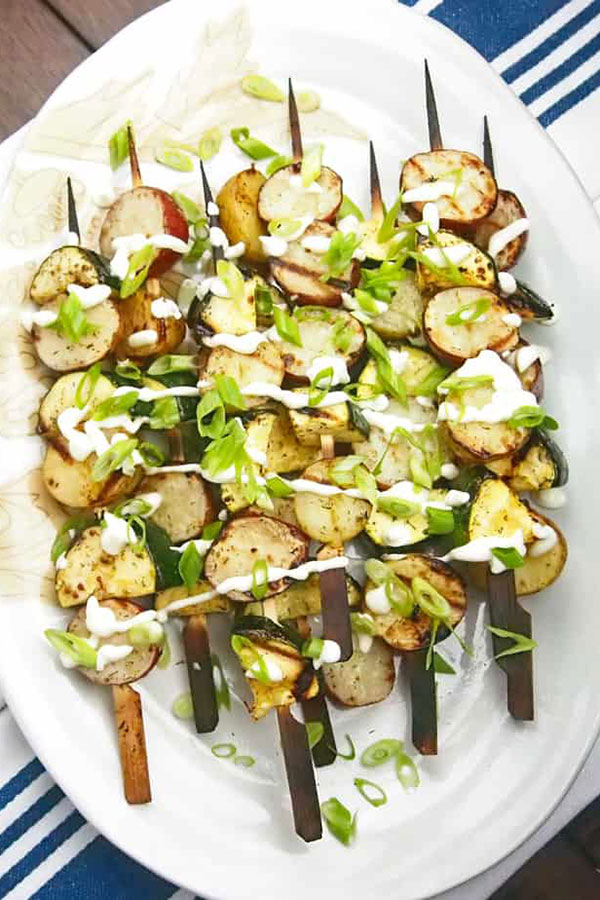 an oblong white platter piled with grilled potato skewers