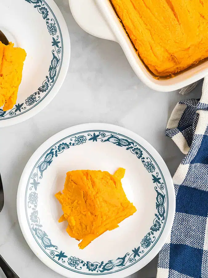 a plate of carrot souffle sitting on a table next to a full casserole of the same