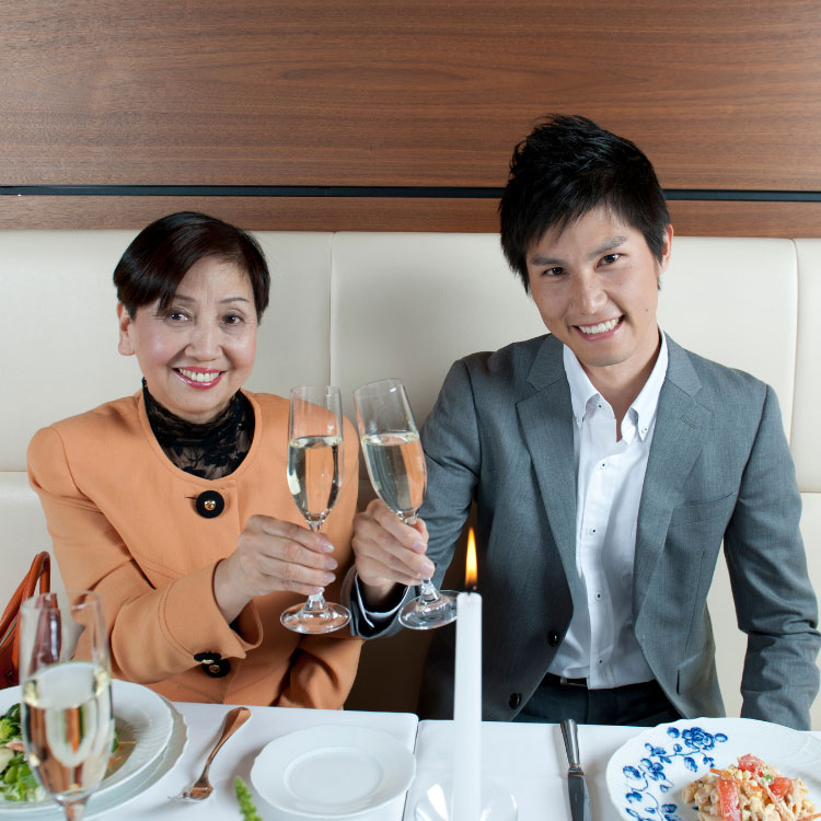 a mother and son toasting flutes of water at a nice restaurant