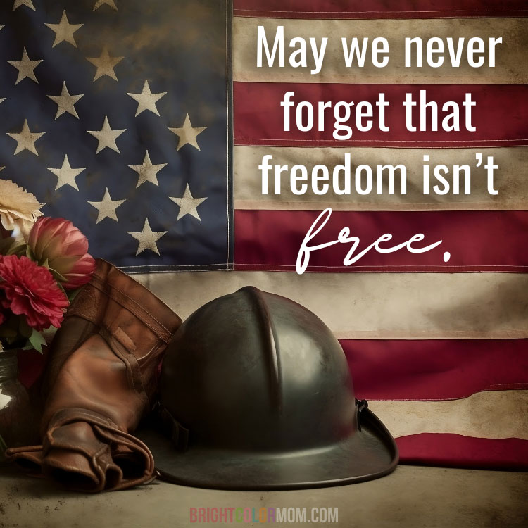 a gritty image of an American flag behind some flowers, boots, and a soldier's helmet, with a text overlay: "May we never forget that freedom isn't free."