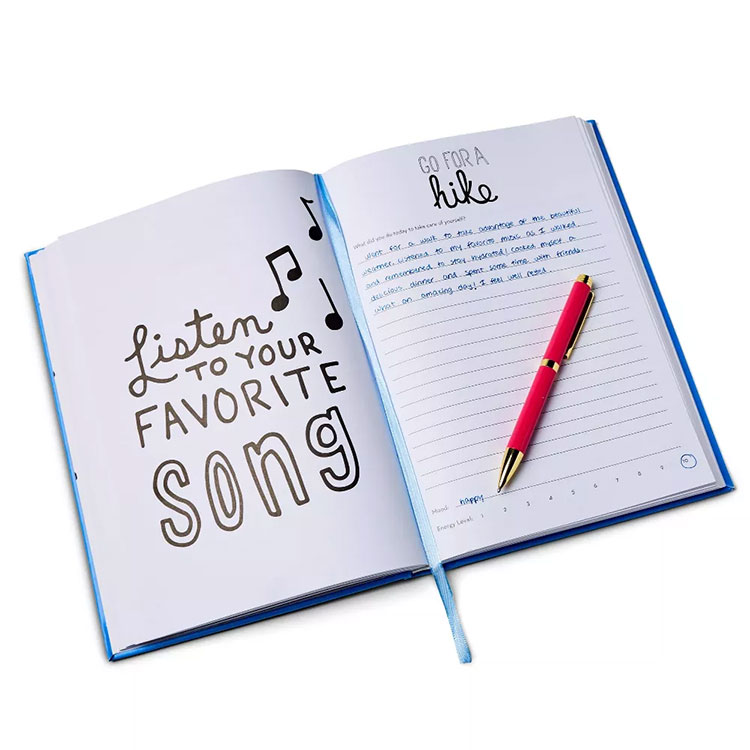 an open self-care journal with the page on the left saying "Listen to your favorite song" and the page on the right has lines for writing with "Go for a hike" at the top