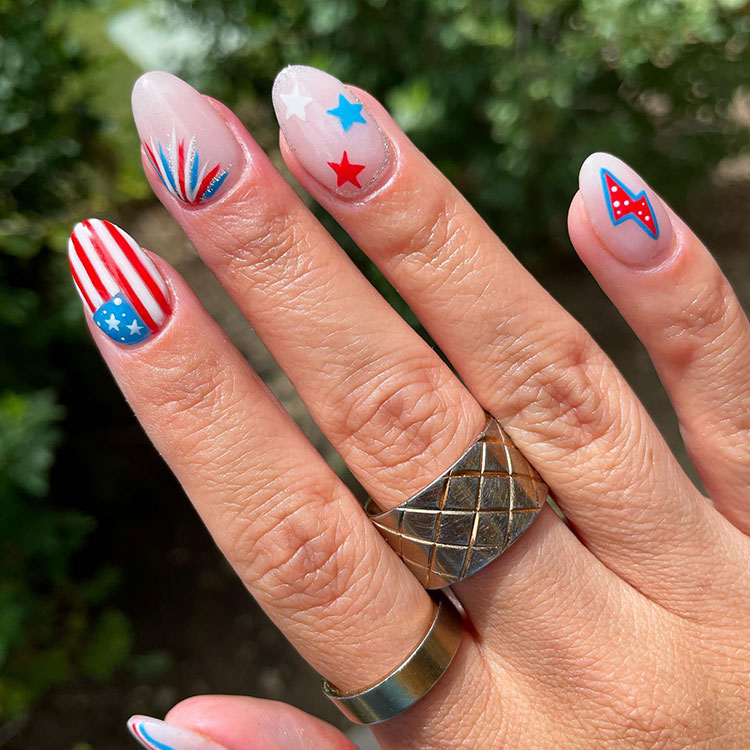 almond-shaped gel nails featuring various designs including an American flag, fireworks, stars, and a lightning bolt