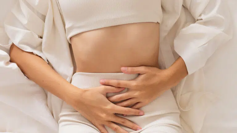 closeup of a woman holding her stomach while lying in bed