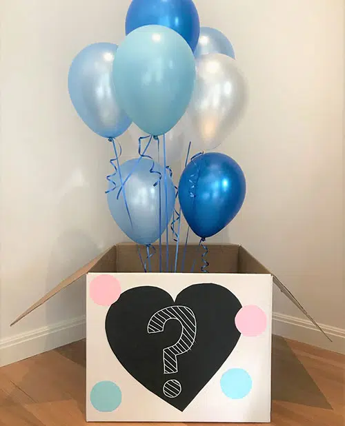 a gender reveal box opened to reveal blue balloons floating out