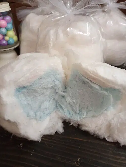 white cotton candy is pulled in half to reveal blue cotton candy in the center