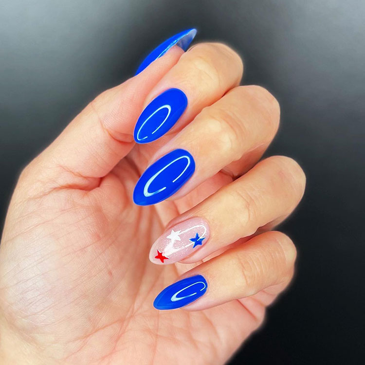bright blue almond-shaped nails with a nude accent nail featuring red, white, and blue stars