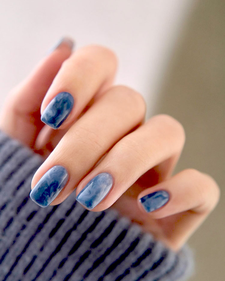 squoval nails painted in a marbled blue polish