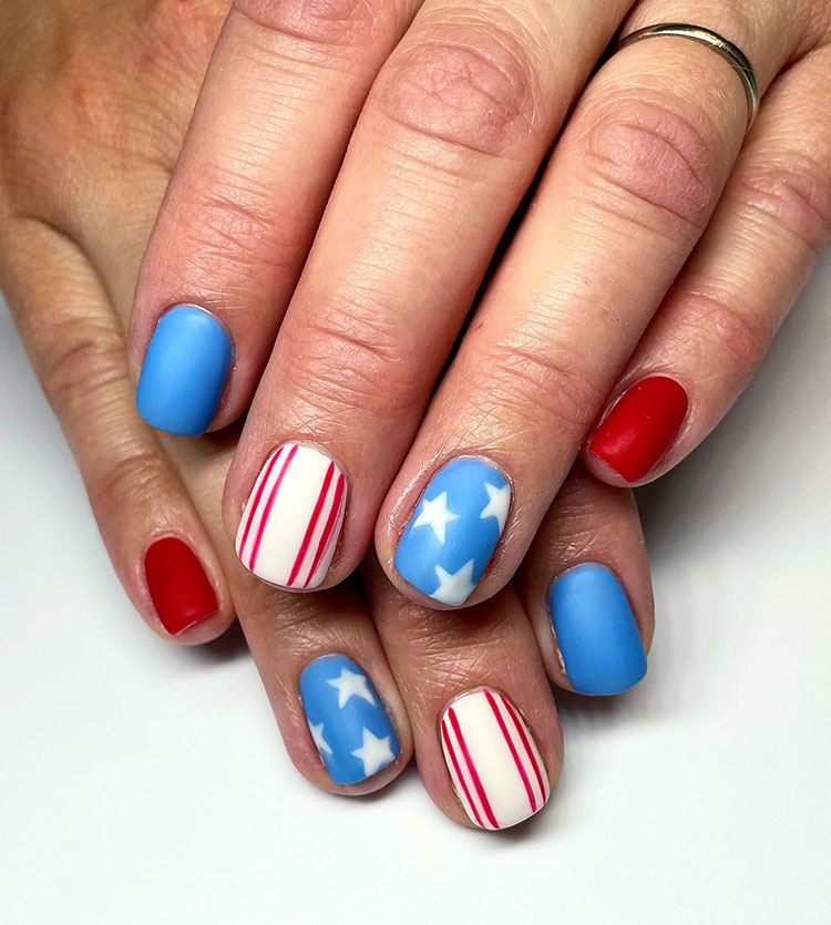 short round nails painted matte in red, white, and light blue with stripes and stars