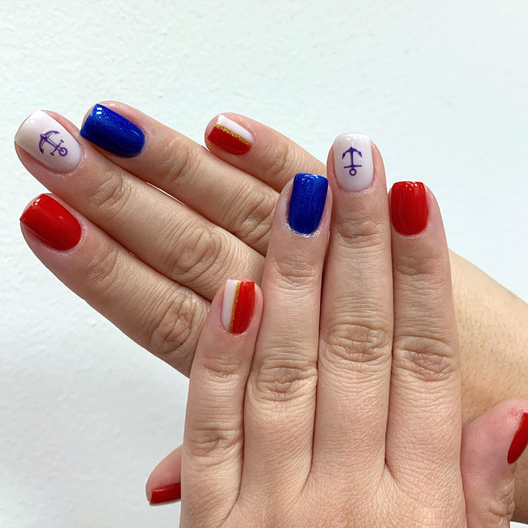 square nails painted red, white, and blue with a blue anchor decal on the white nails