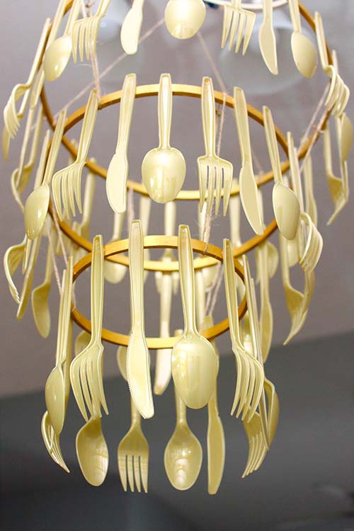 a high-angle view from below of a gold cutlery chandelier hanging from the ceiling