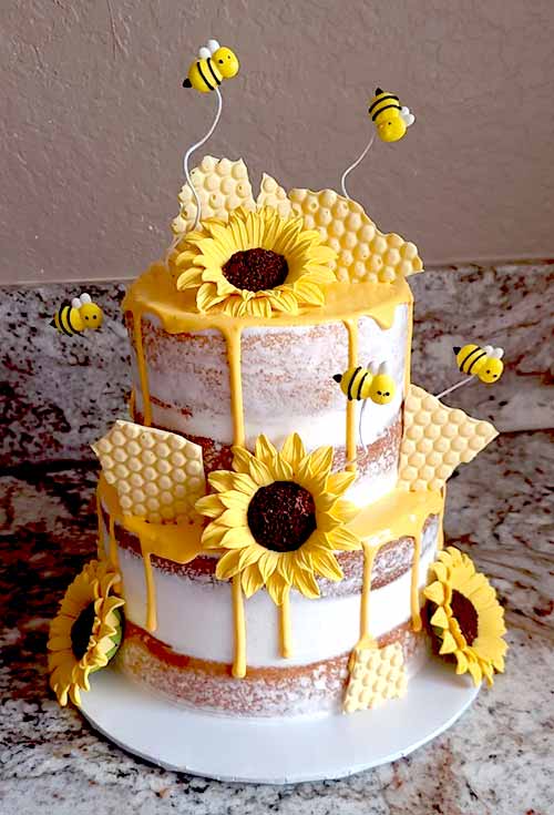 a two-tier cake featuring honeycombs, bees, and sunflowers