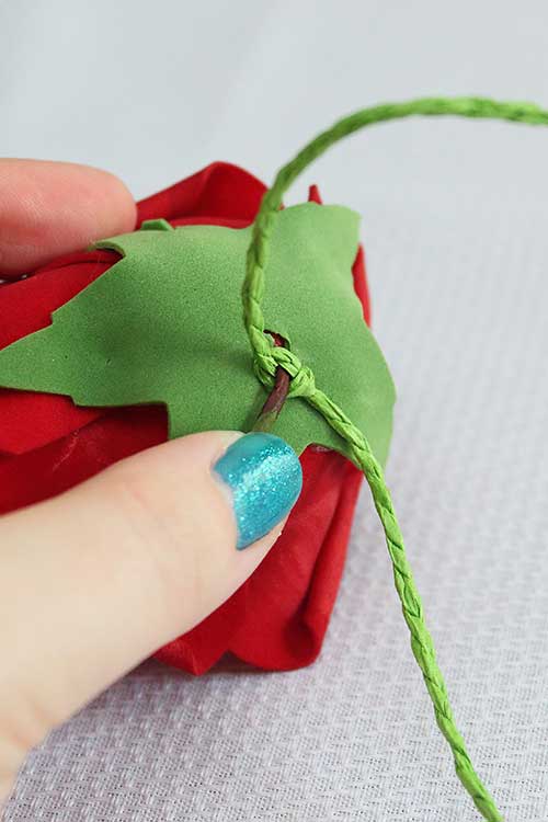 closeup showing a wire stem being bent to lie flat against a rose bloom