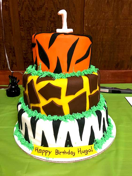 a homemade three-tier safari birthday cake, each tier a different jungle animal print (tiger, giraffe, and zebra)