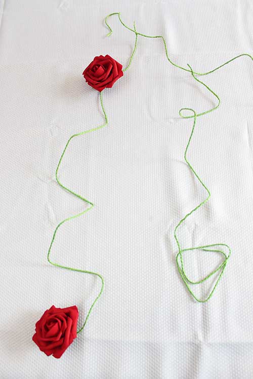 green paper rope with silk roses attached lying on a white table