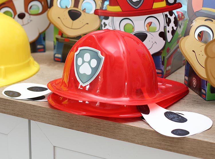 a red plastic fire hat with a Paw Patrol sticker on the front and paper Dalmation ears under the sides