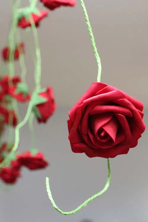 a side view of a DIY rose garland with the focus on a single bloom in the foreground and the rest in bokeh