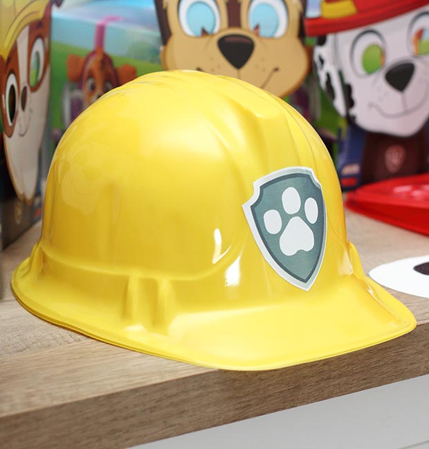 a plastic yellow construction helmet with a Paw Patrol badge sticker on the front