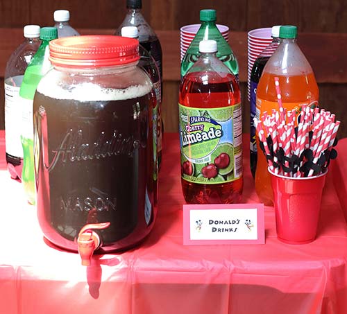 a variety of party drinks and paper straws with Mickey heads attached, as well as a card that reads "Donald's Drinks"