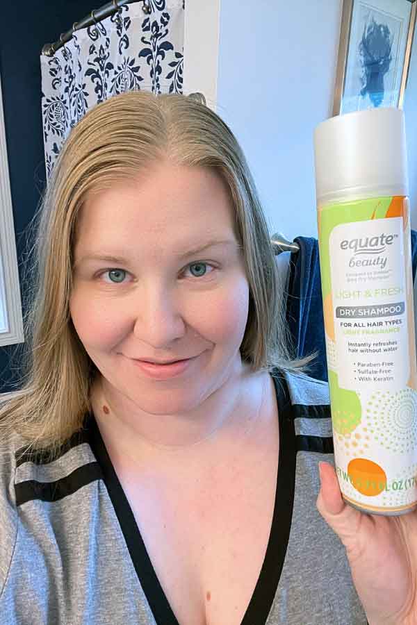 woman holding up can of Equate dry shampoo
