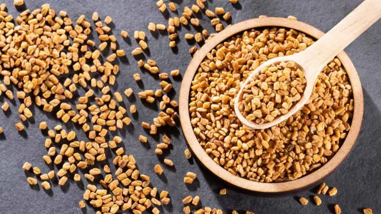 a bowl of fenugreek seeds overflowing onto a dark table