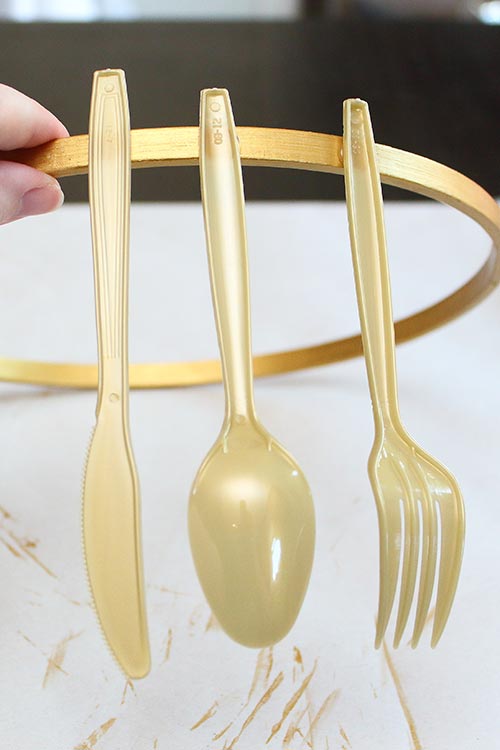 a gold knife, spoon, and fork attached to a gold hoop