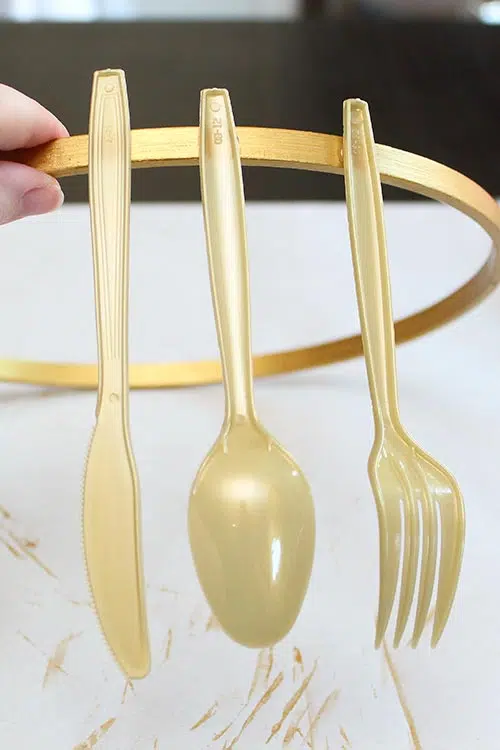 a gold knife, spoon, and fork attached to a gold hoop