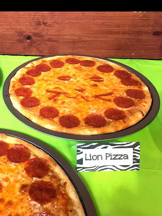 a homemade pizza resembling a lion's head with a food card labeled "Lion Pizza"