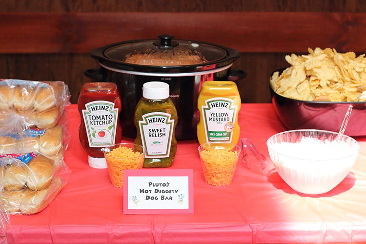 hot dogs in a crockpot with toppings and a card that reads "Pluto's Hot Diggity Dog Bar"