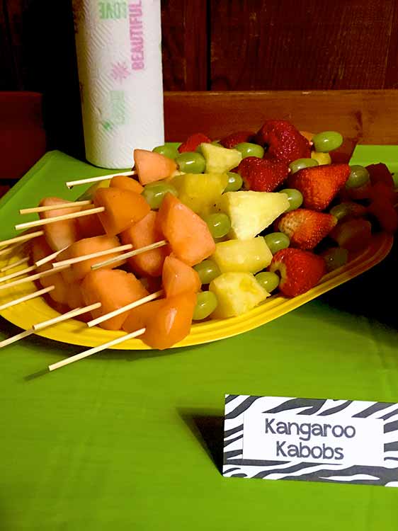 a platter of fruit skewers with a food card labeled "Kangaroo Kabobs"